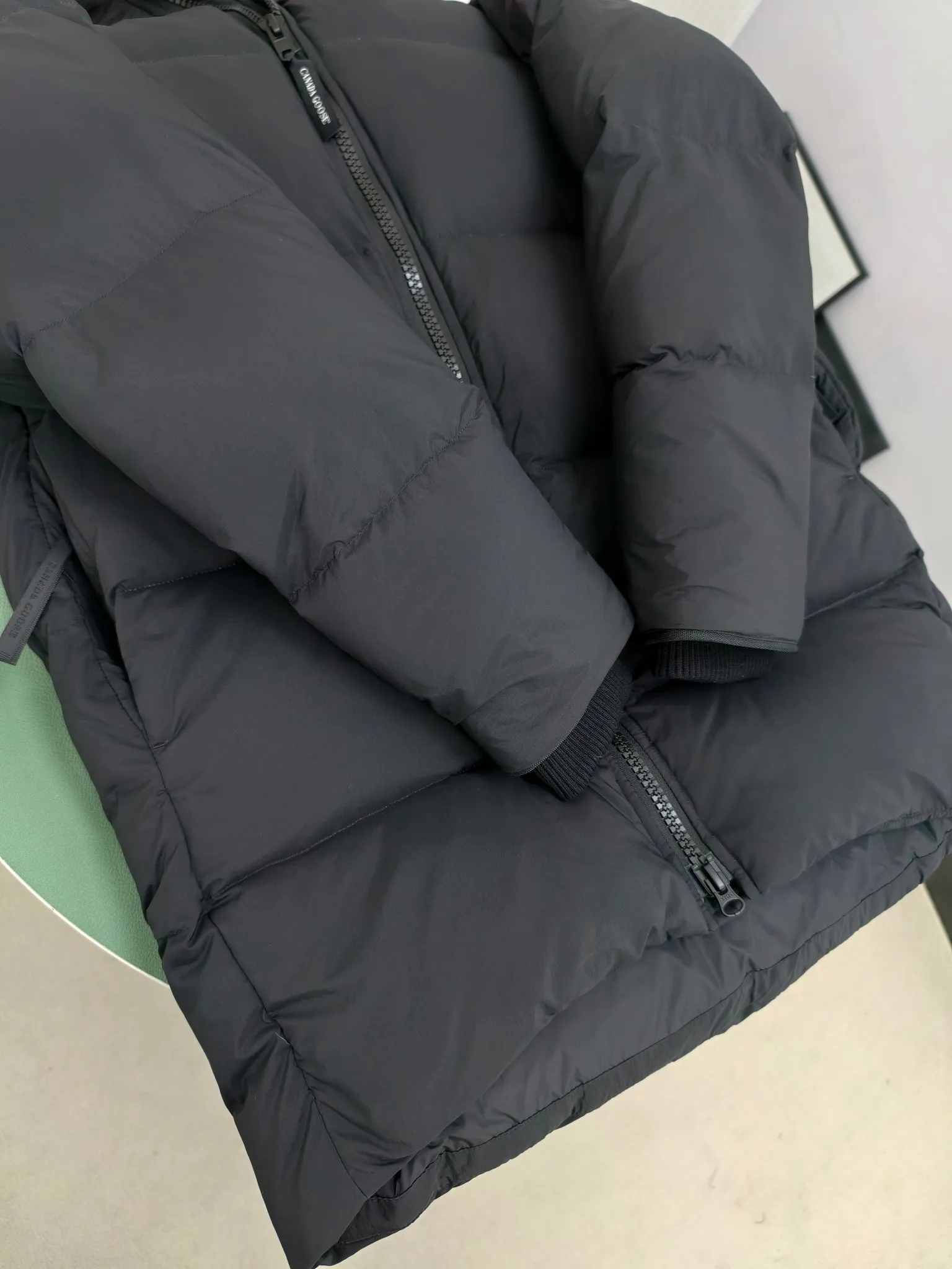 P940 Canada Goose Lawrence Down Jacket The Lawrence Down Jacket provides essential protection for everyday adventures and is made from sustainable Enduraluxe fabric with a durable soft touch. It features a quilted body, an adjustable down hood and a longer hem. Adjustable, down-filled, communicated hood. Two-way center front zipper increases range of motion and ventilation. The chin-protecting suede knit stand-up collar is soft and extra-comfortable. Inset rib-knit cuffs for added comfort and locked in heat. CORDURAD piping at the cuffs hem and reflective double-stripe grip tape at the back. Internal shoulder strap Color: black with red label black with black label azure blue Size: XS-2XL